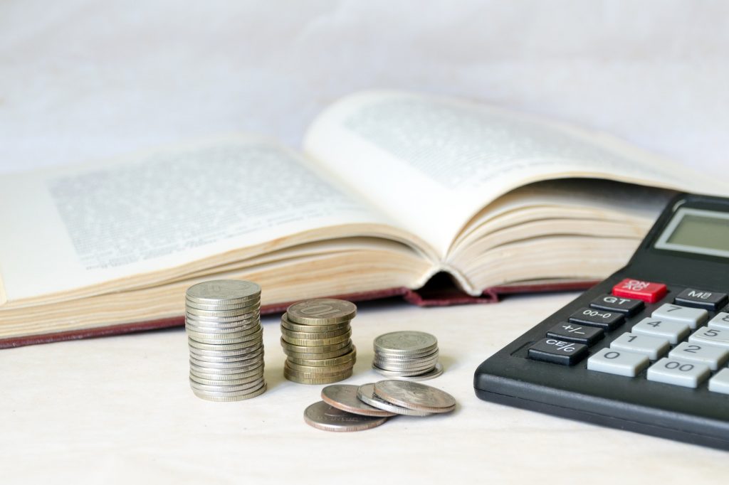a-stack-of-coins-and-a-calculator-in-front-of-an-open-book-1024x682