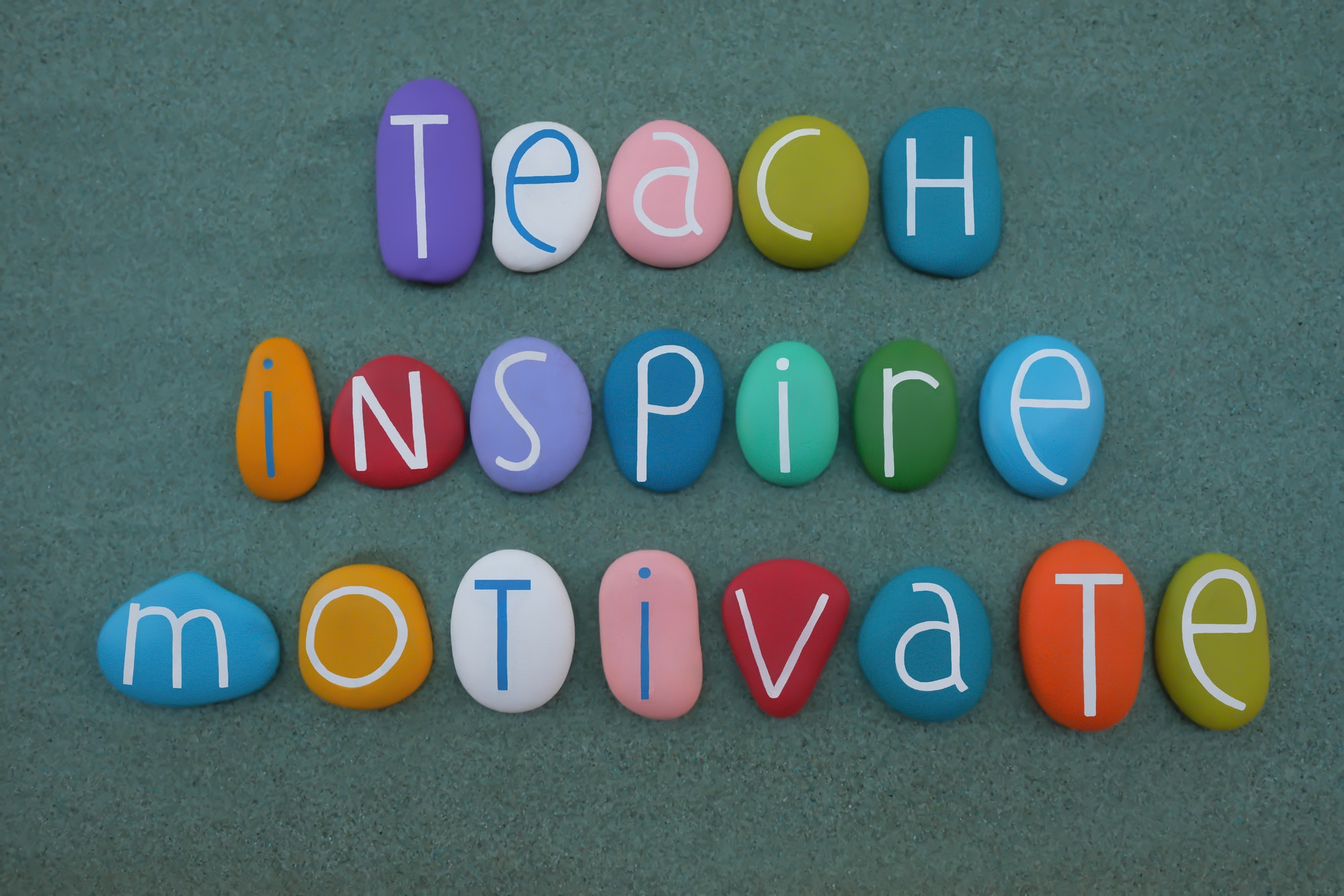 Teach, Inspire, Motivate, creative quote, educational text composed with multicolored stone letters